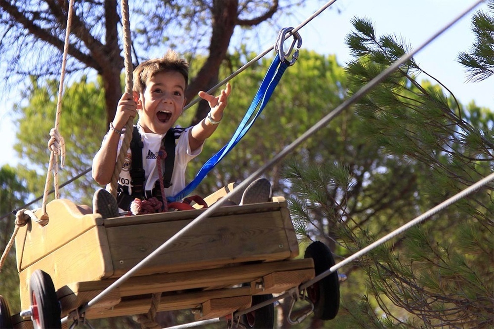 un niño con una camiseta adidas blanca y negra se sienta en un carro de madera
