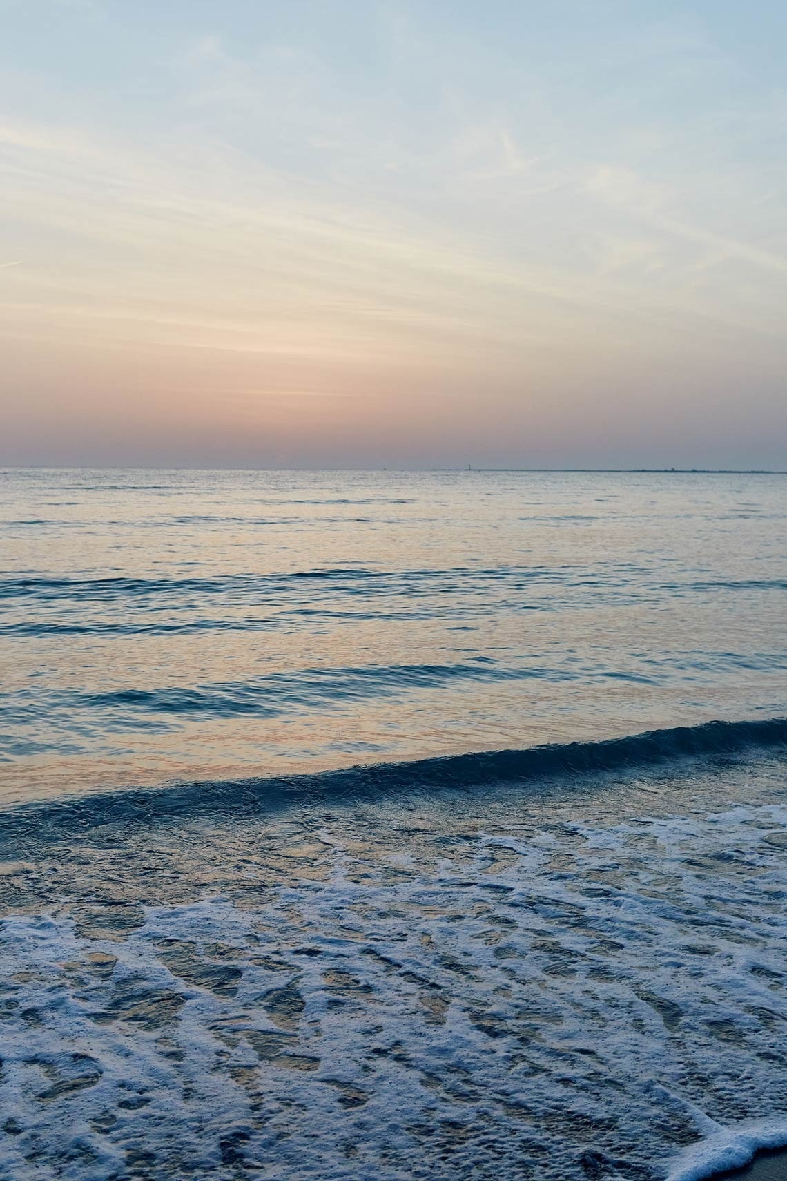 a sunset over the ocean with waves crashing on the beach