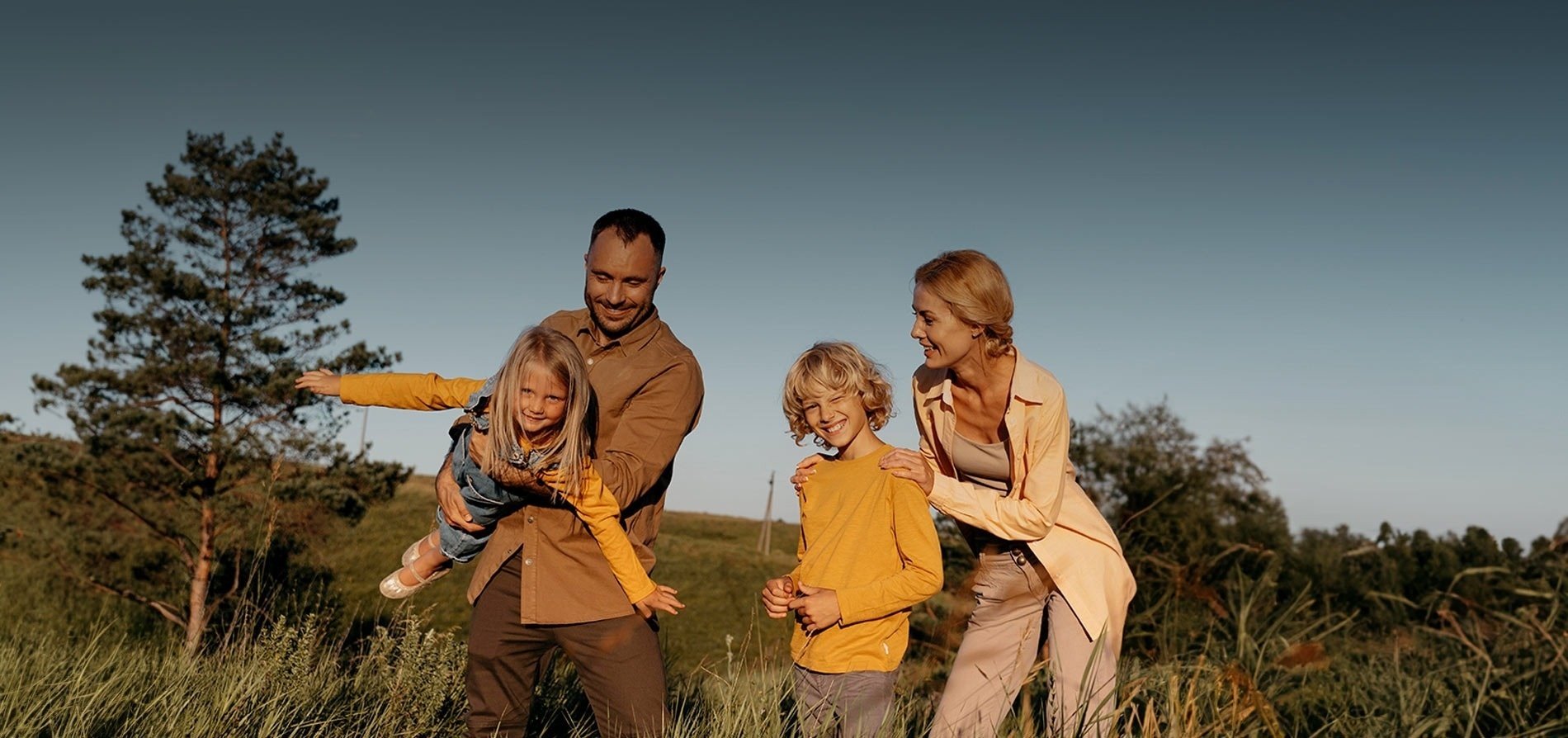 a family standing in a field with trees in the background