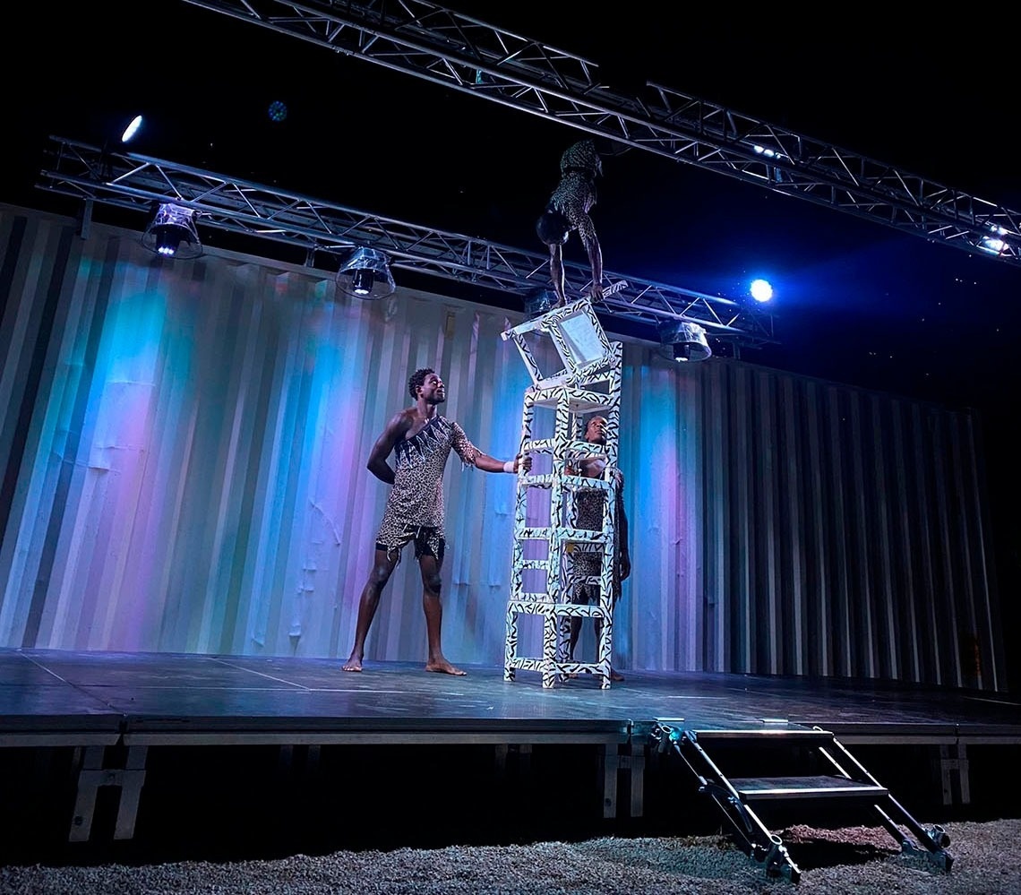 a man stands on a ladder while another man stands on a chair