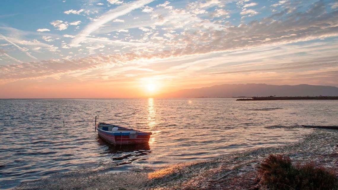 een boot in het midden van de oceaan bij zonsondergang