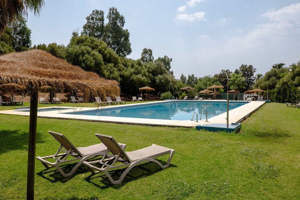 a large swimming pool surrounded by chairs and umbrellas