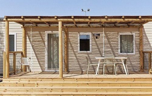 una casa móvil con una mesa y sillas en el porche .