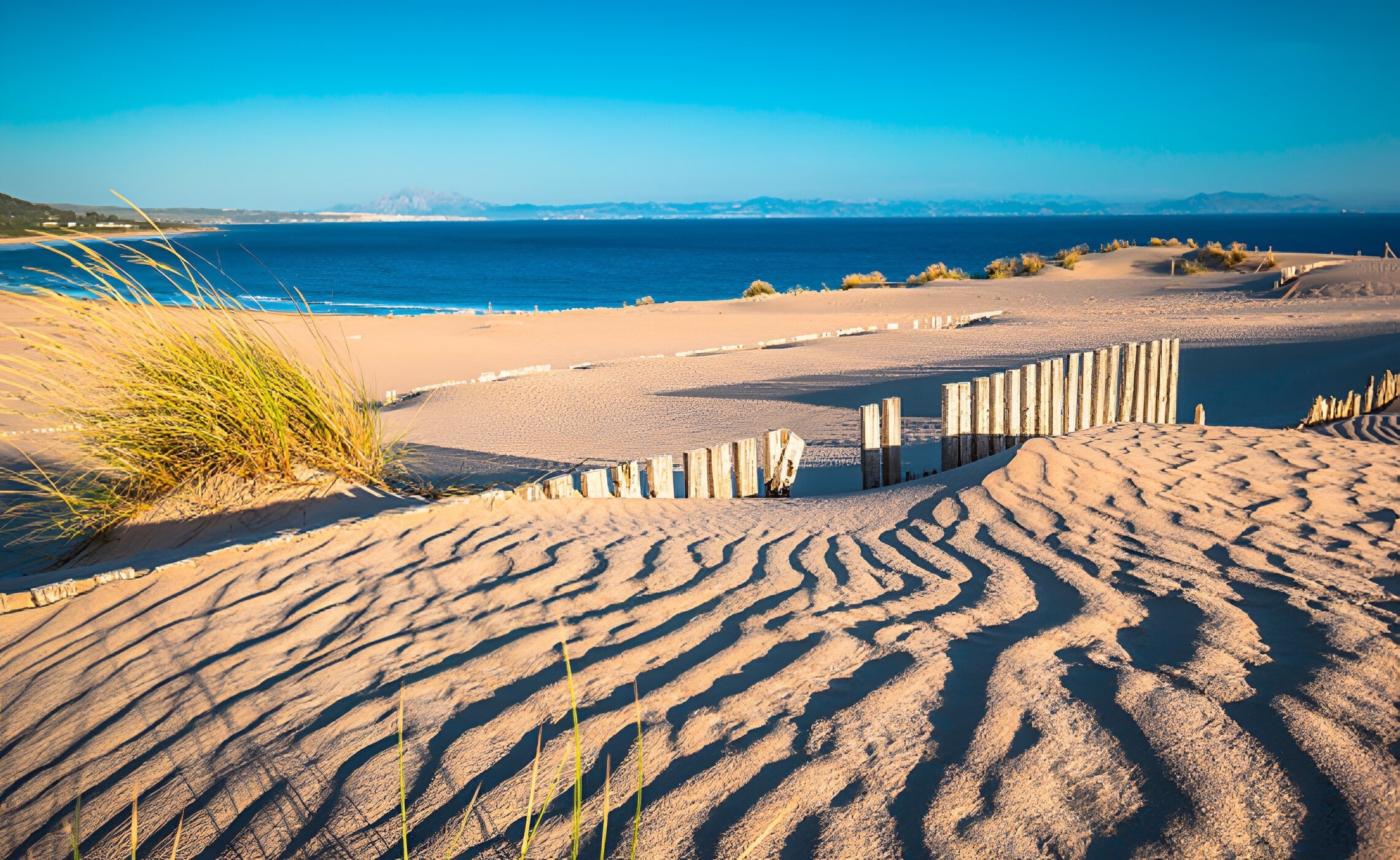 una duna de sable amb una cerca de madera al fons