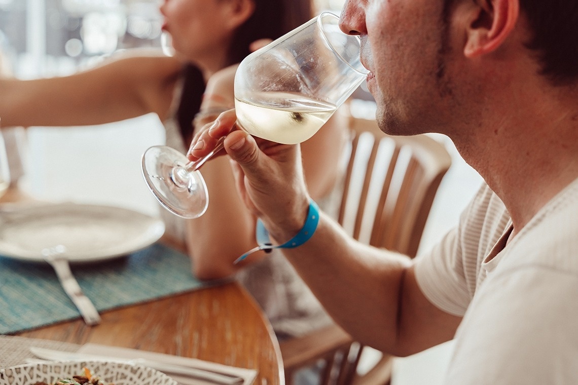 ein Mann sitzt an einem Tisch und trinkt Wein aus einem Glas