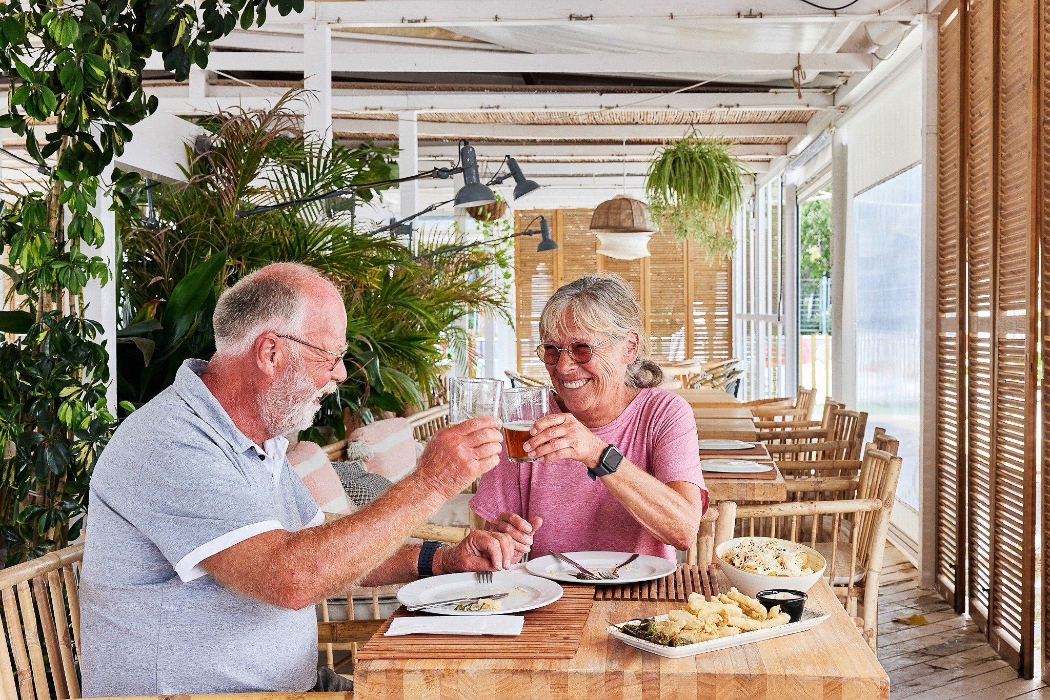 een man en een vrouw zitten aan een tafel met eten en drinken