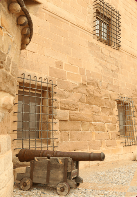 un viejo cañón de madera se sienta frente a una pared de ladrillo