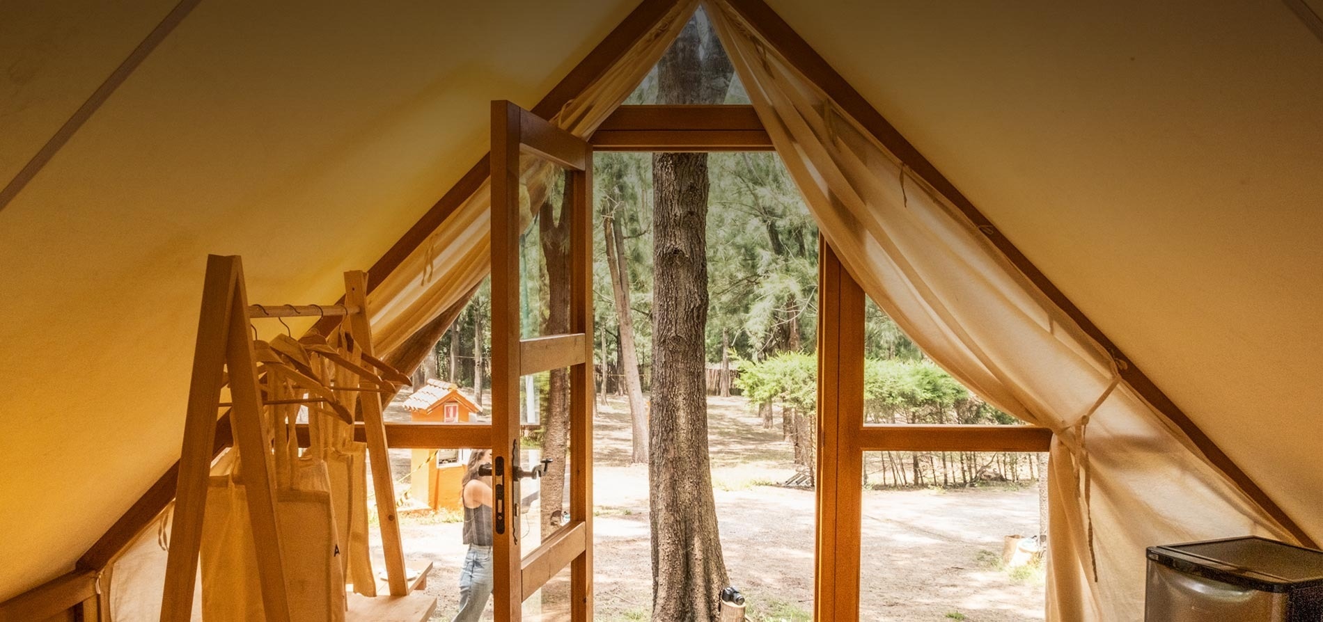 een tent met een groot raam met uitzicht op een bos