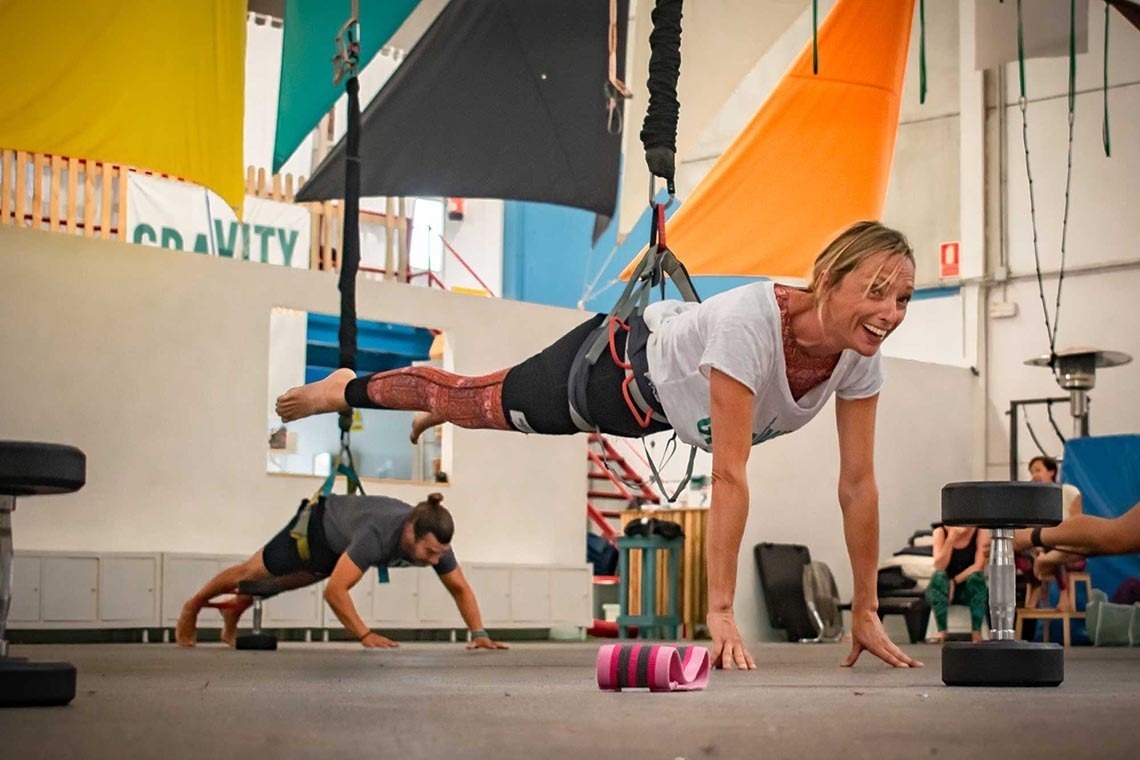 a woman is doing push ups in front of a sign that says gravity