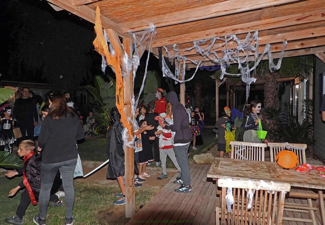 un grupo de niños en disfraces de halloween se reúnen en un patio decorado para halloween