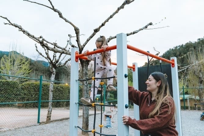 Niña y mujer juegan en parque infantil. Diversión familiar al aire libre en nuestro hotel.