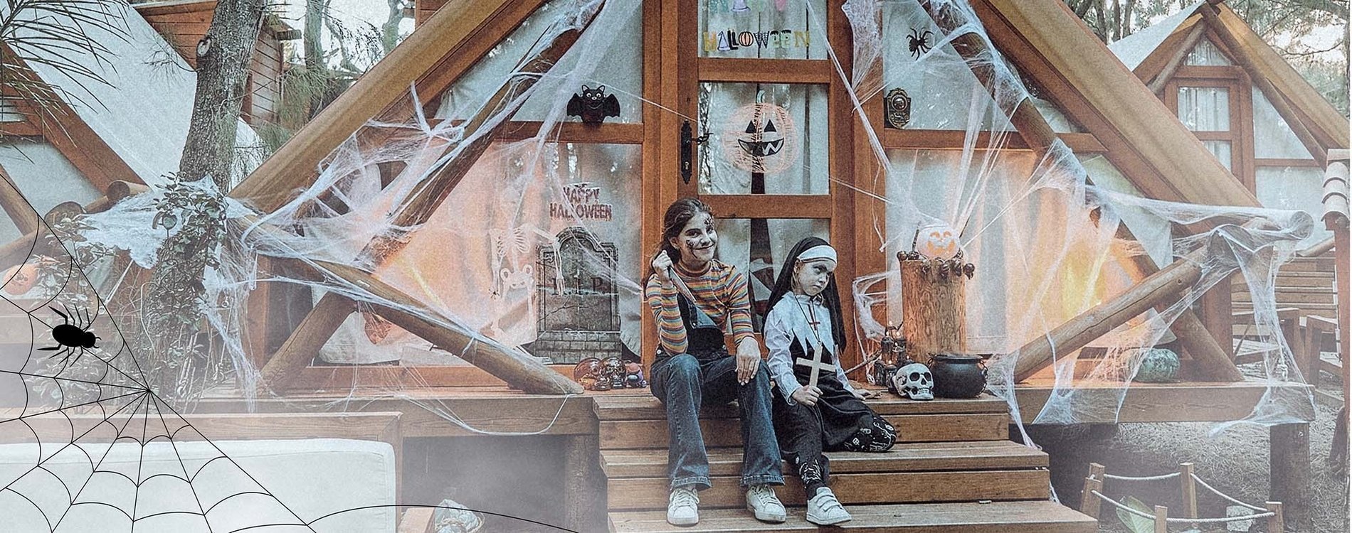 two girls are sitting on the steps of a house decorated for halloween