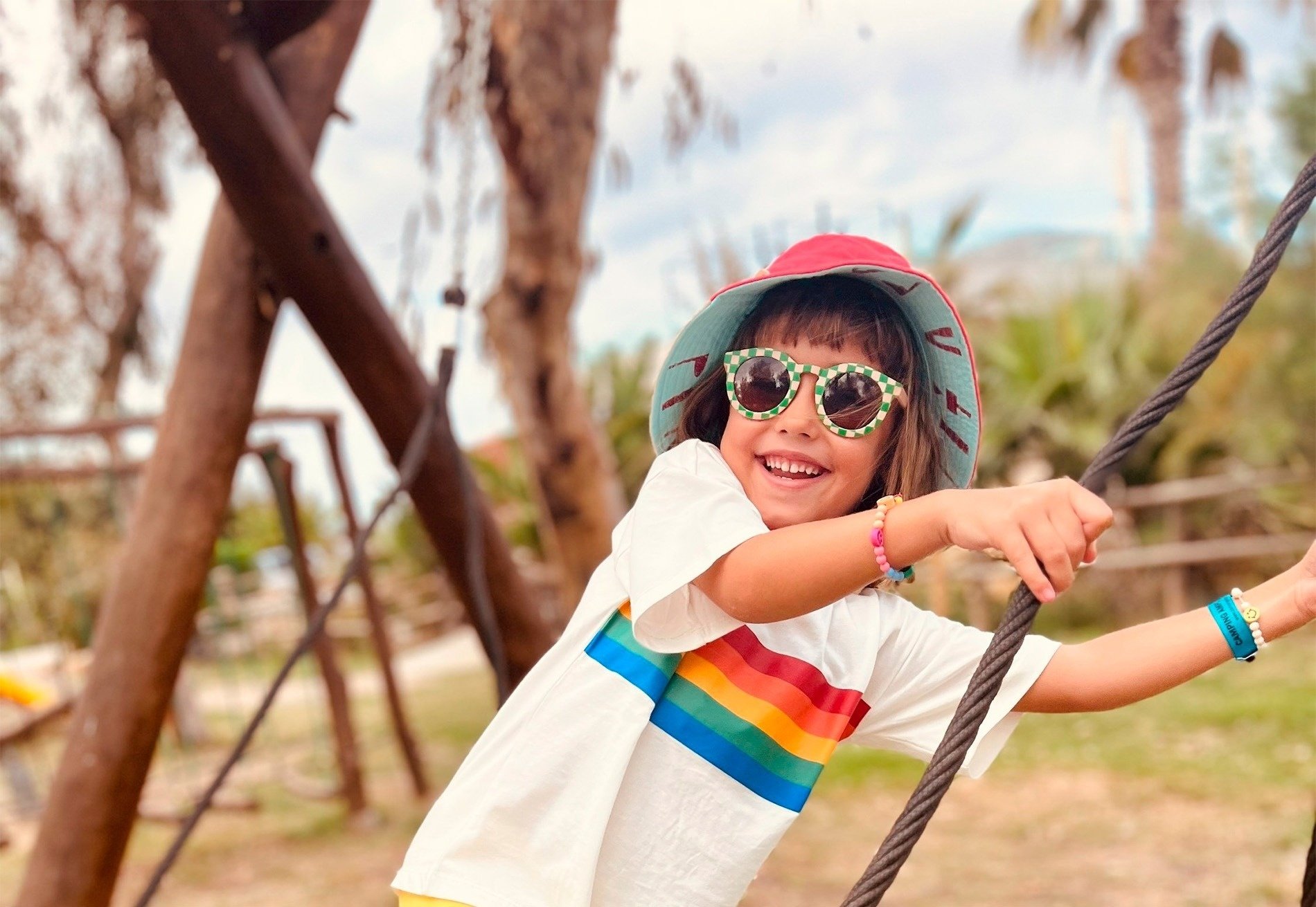 a little girl wearing sunglasses and a rainbow shirt