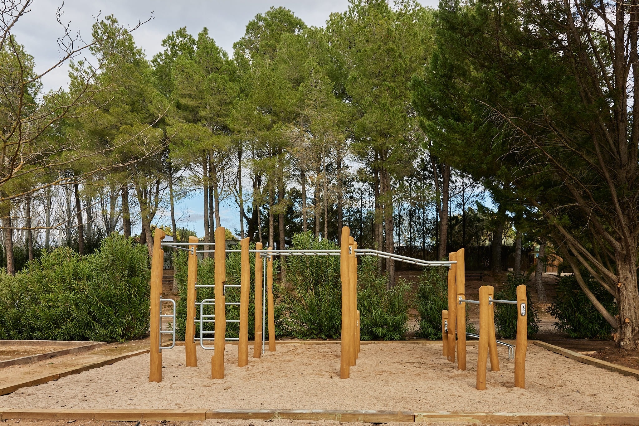 un área de juegos de madera en un parque rodeado de árboles