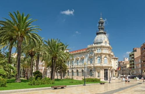 un hombre con una mochila y un sombrero se para en un acantilado mirando al océano