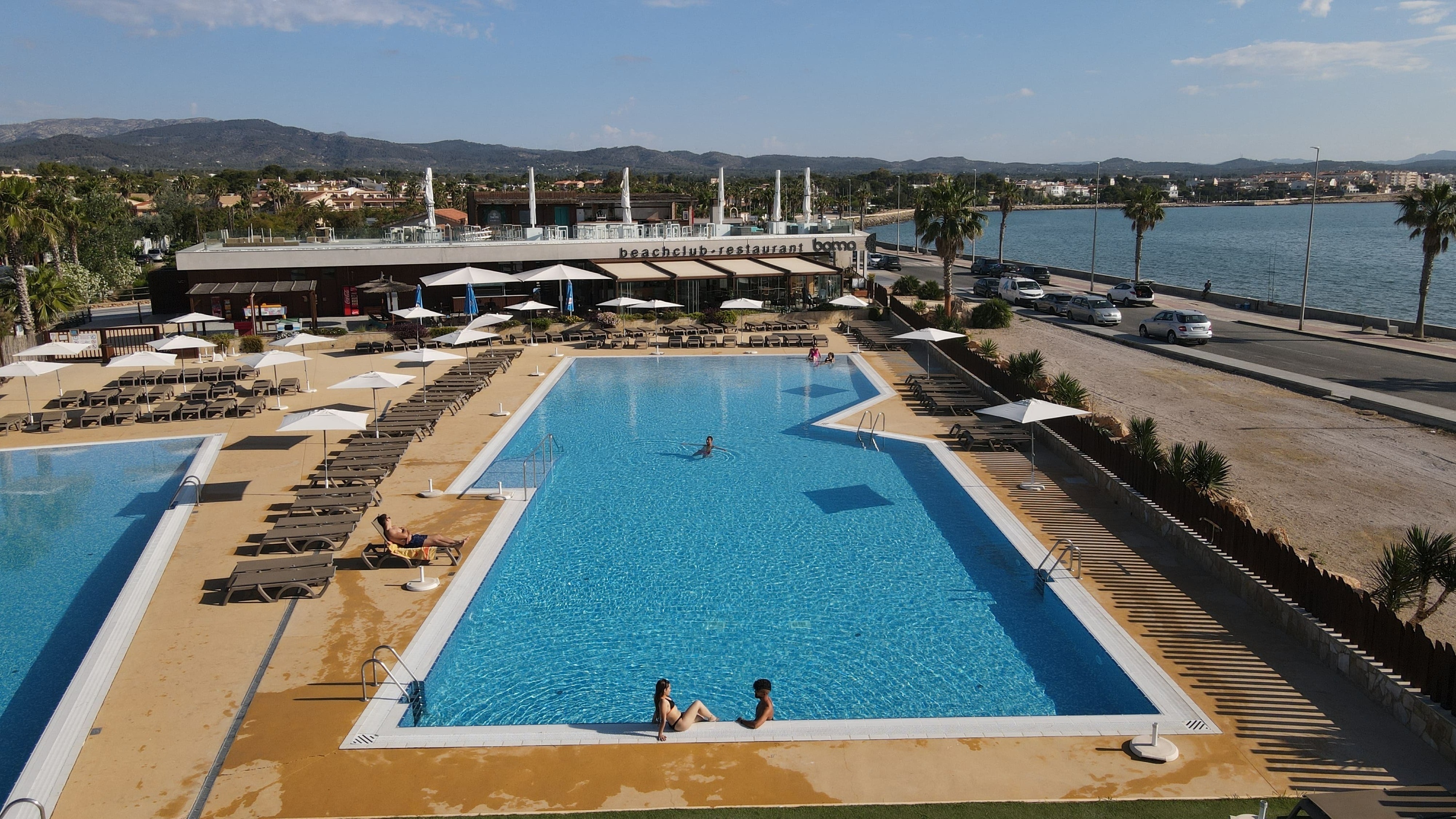 a large swimming pool is surrounded by chairs and umbrellas
