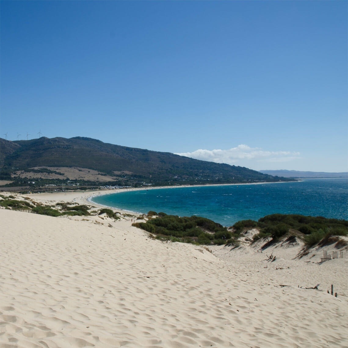 a sandy beach with mountains in the background