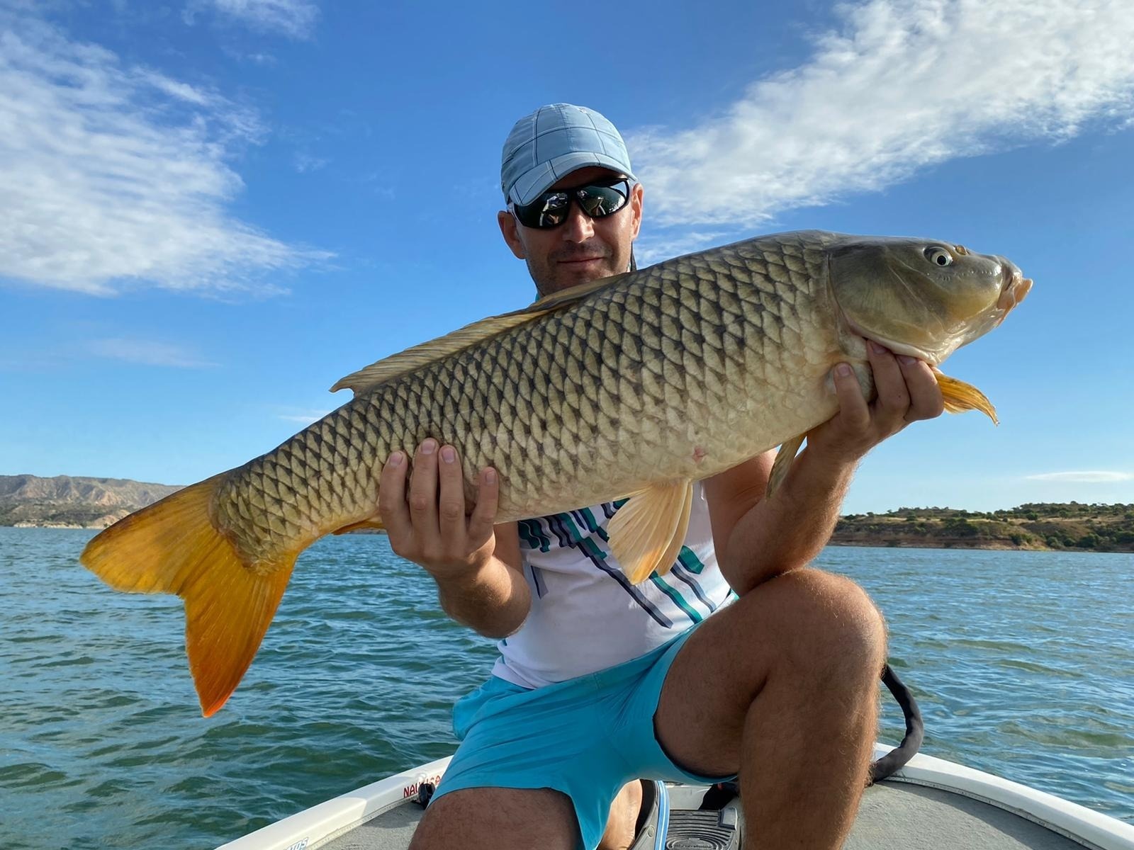 a man sitting on a boat holding a large fish