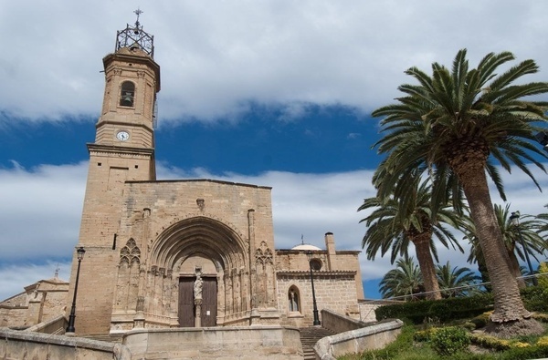 une vieille église avec une tour de l' horloge à côté d' un palmier