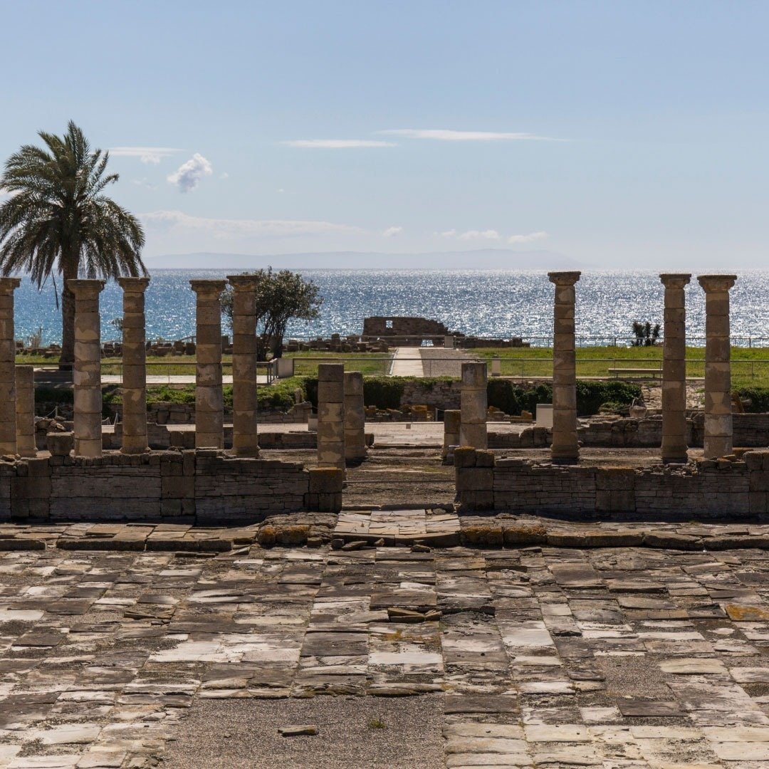 eine Reihe von Säulen in einem alten Gebäude mit Blick auf das Meer