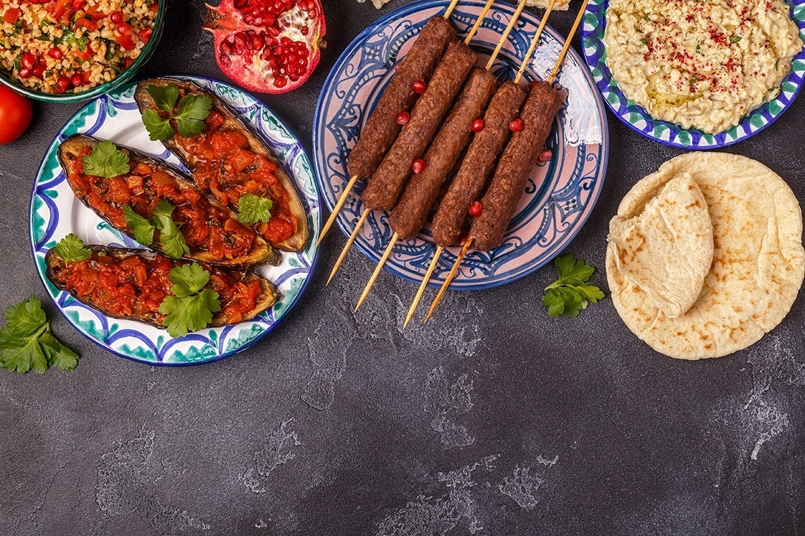 a variety of plates of food including stuffed eggplant and kebabs