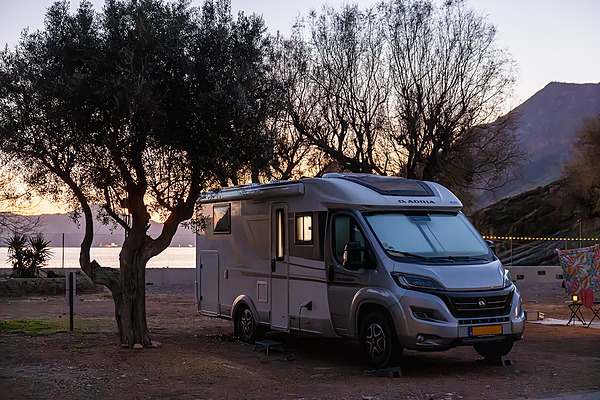Autocaravana en camping junto al mar con árboles y montañas en Murcia