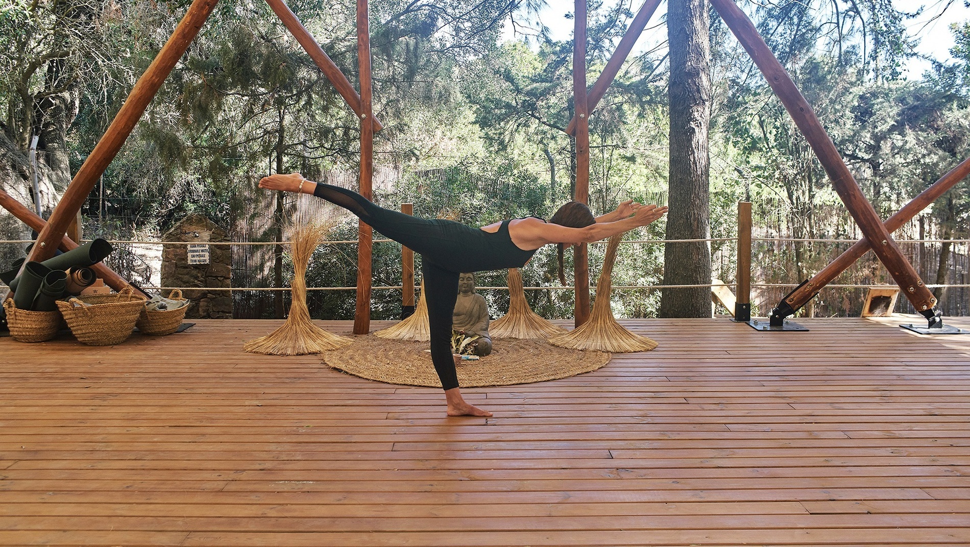 une femme fait une pose de yoga sur une terrasse en bois