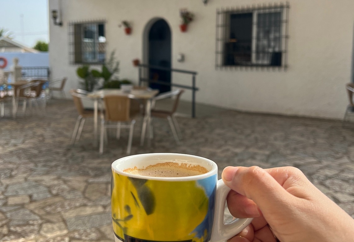 a person is holding a cup of coffee in front of a white building