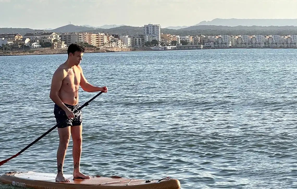 Hombre haciendo paddle surf en el mar, con vistas a la costa TAIGA.