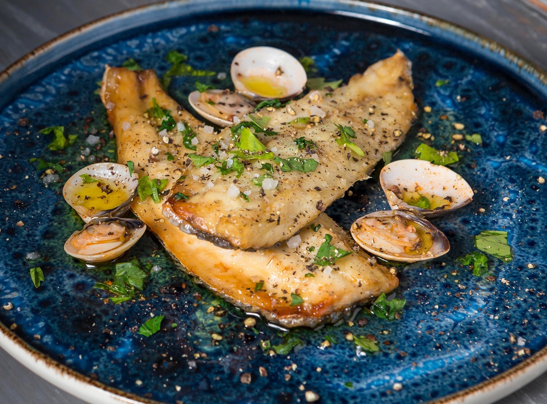 un plato blanco lleno de mejillones con limón y perejil