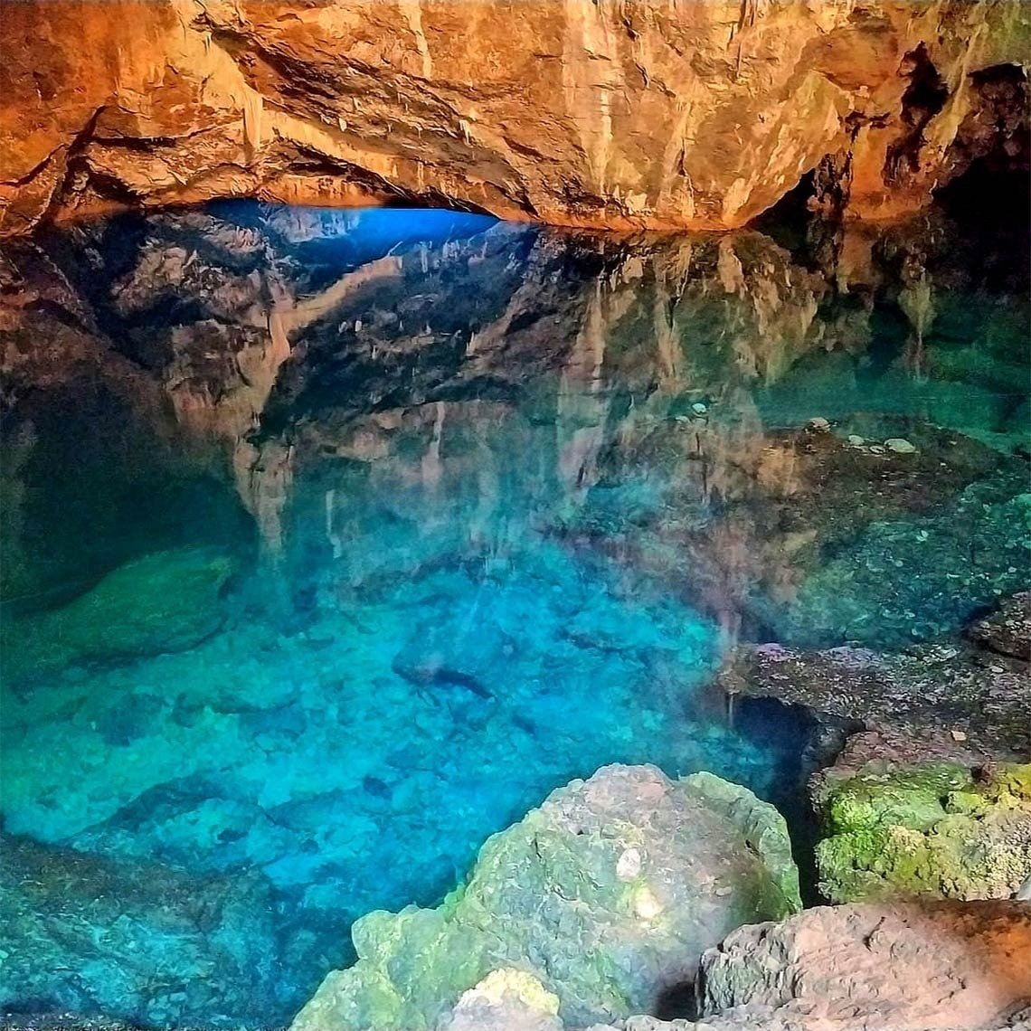 una cueva llena de agua azul y rocas