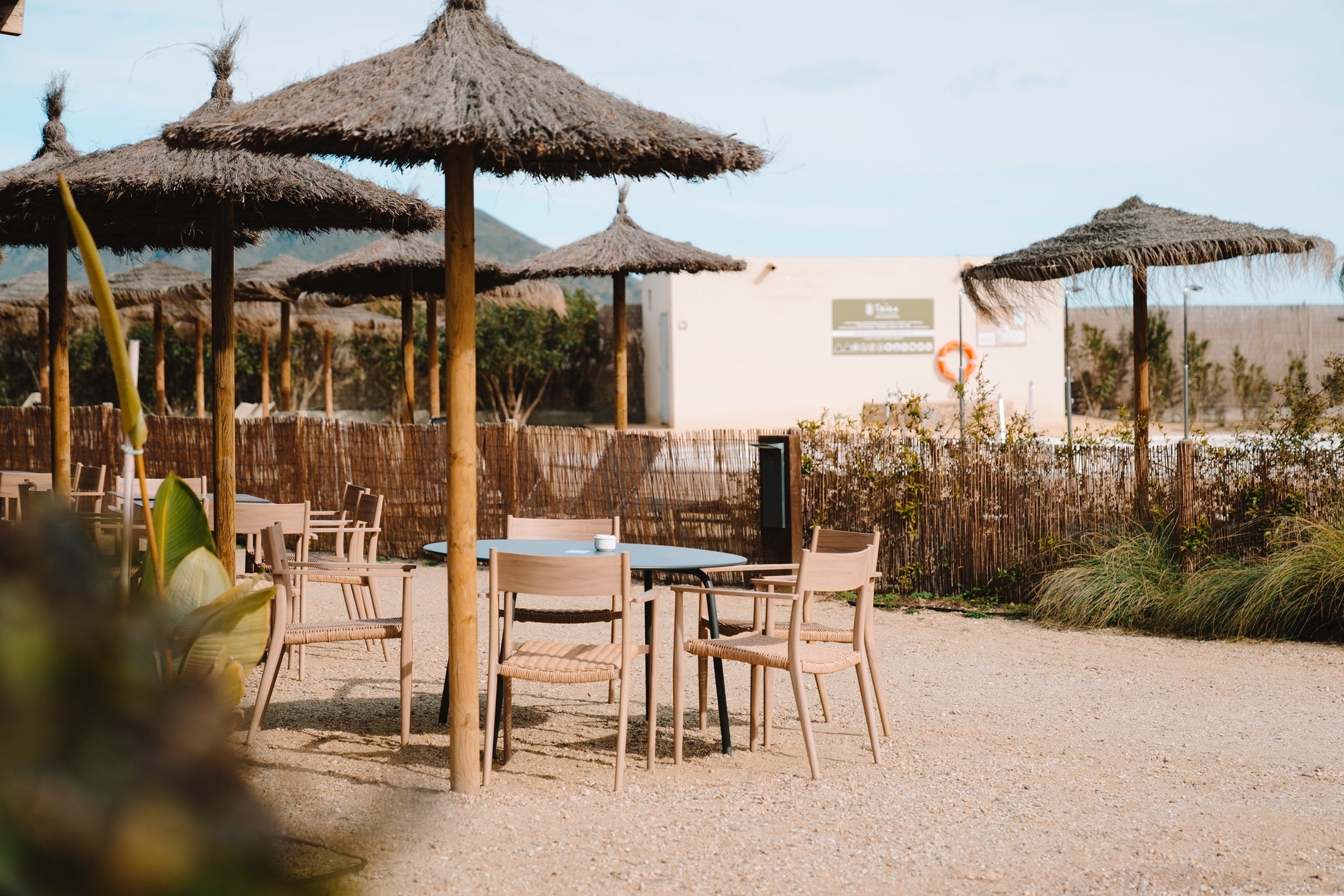Buitenruimte bij Taiga: Corporativa met rieten parasols en houten stoelen, ideaal voor evenementen.