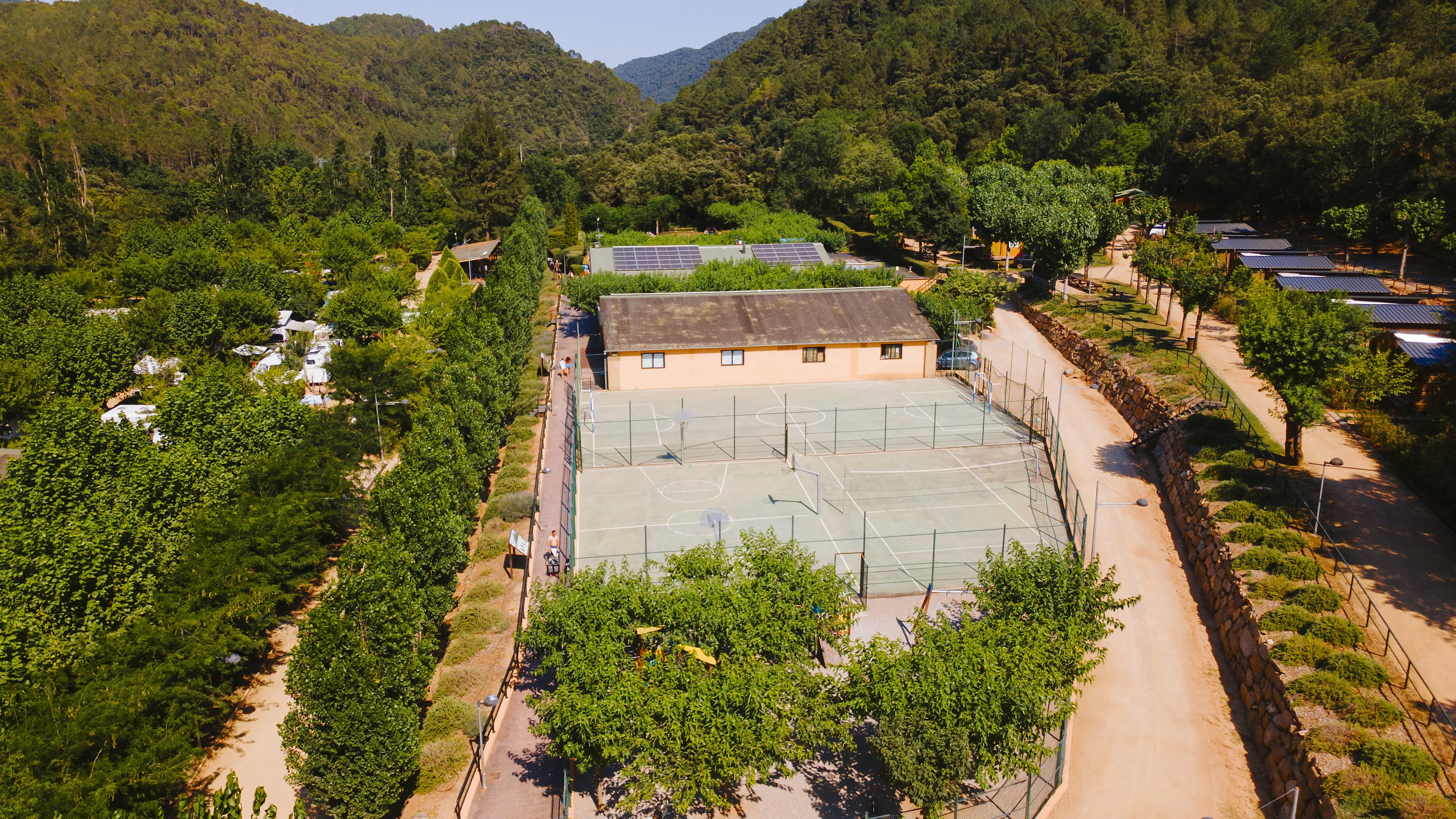 Vista aérea de las canchas deportivas y el complejo hotelero con Taiga: Corporativa entre árboles y montañas.