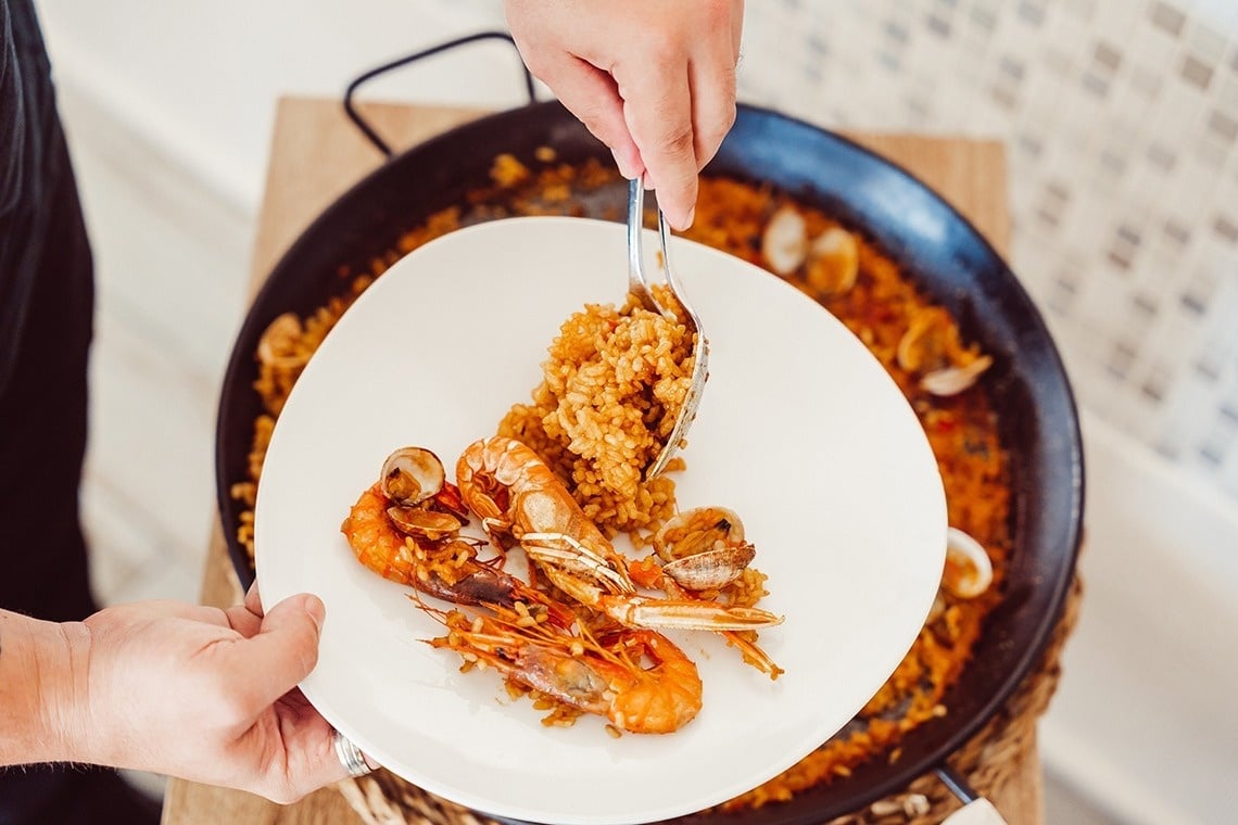 a person is taking a plate of food from a pan