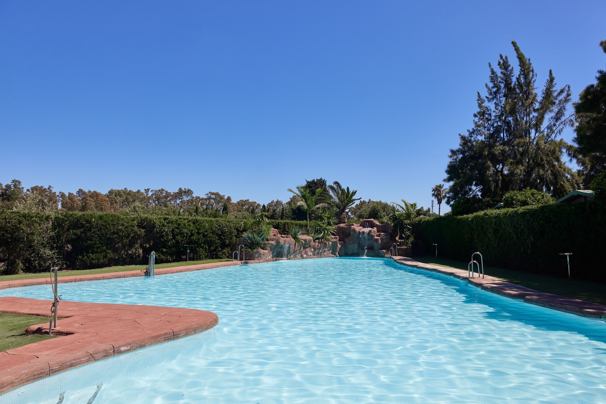 ein großer Swimmingpool mit einem Wasserfall im Hintergrund