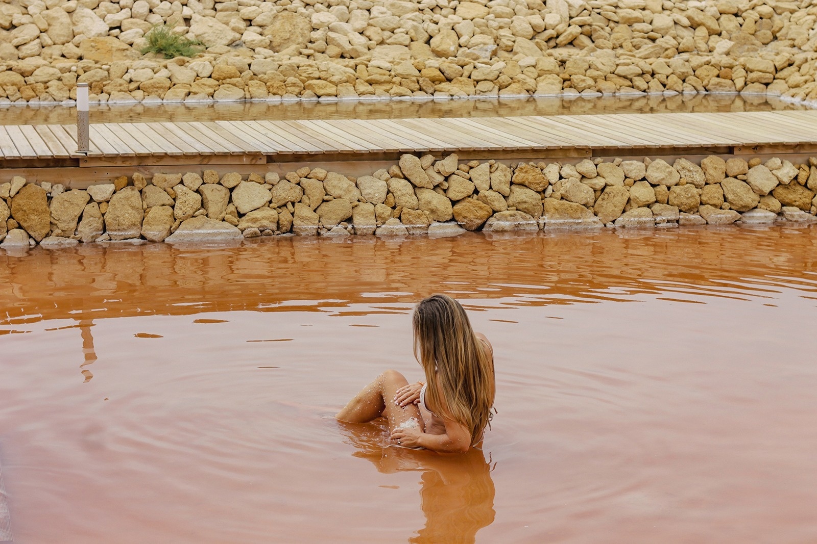 a woman in a bathing suit sits in a body of water