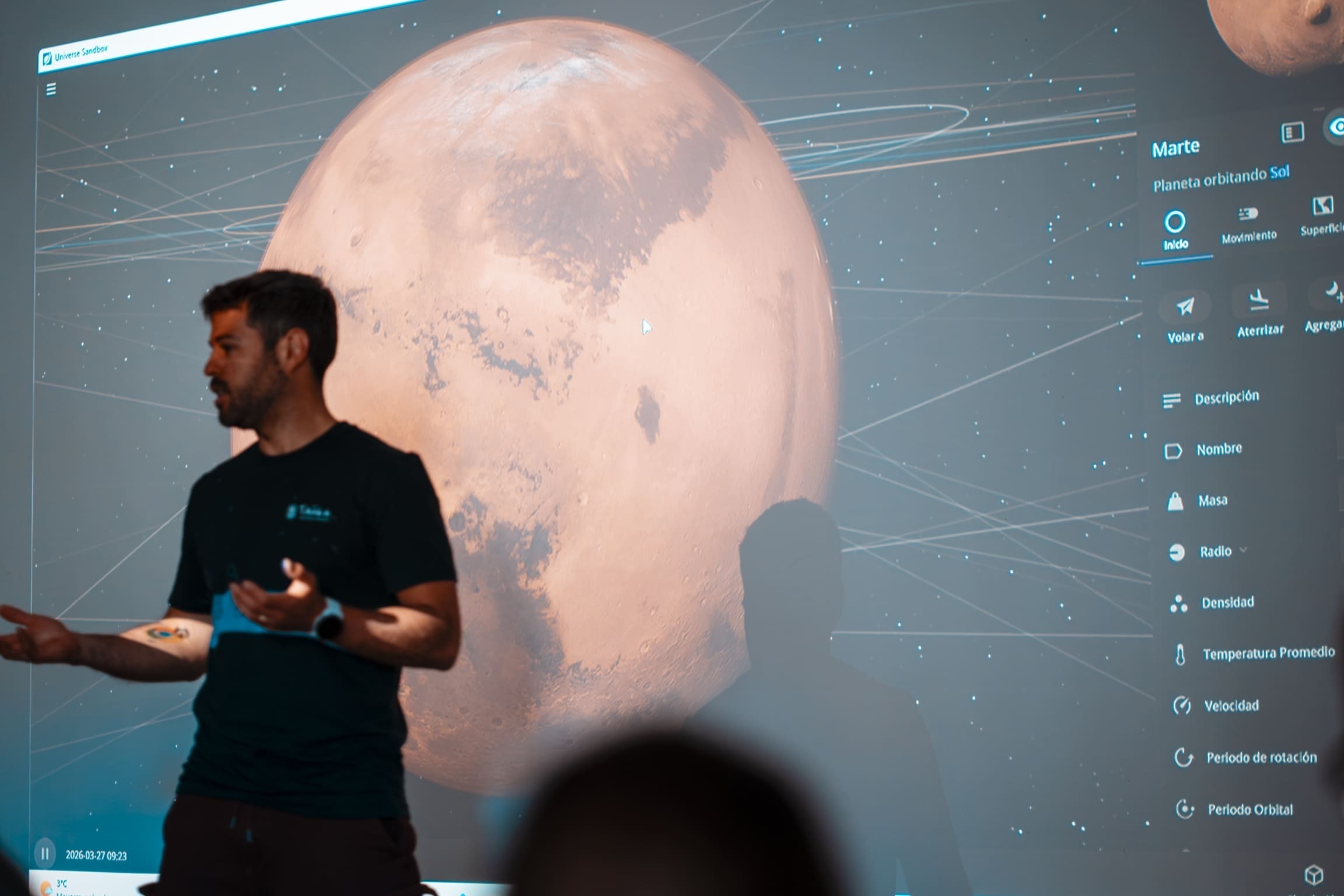 Presentación educativa sobre Marte en pantalla grande, mostrando simulación de Universe Sandbox y datos planetarios.