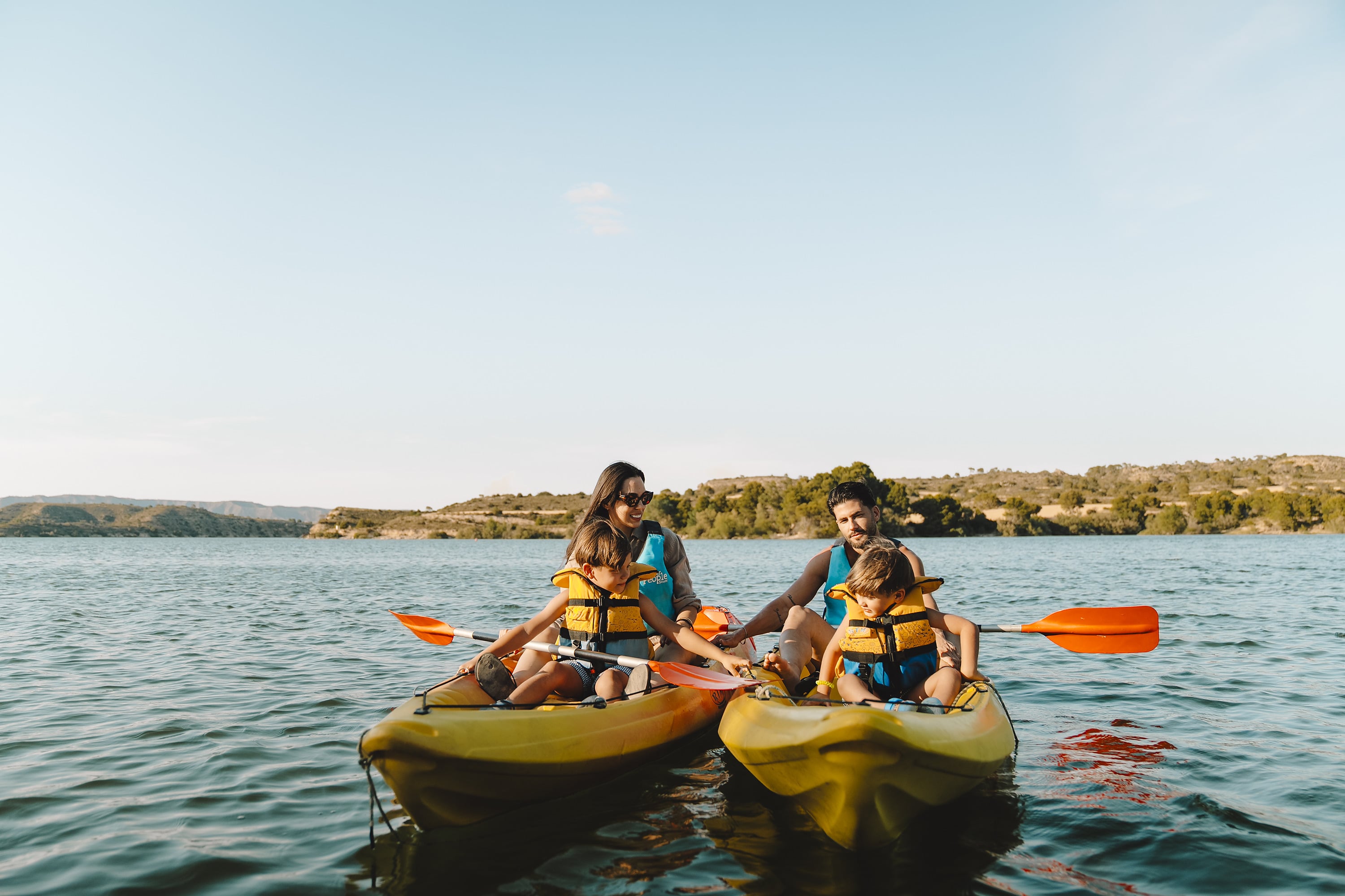 Familia en kayaks con chalecos salvavidas disfrutando del lago y la naturaleza, ideal paraTAIGA Lake Caspe | TAIGA | Campings & Resorts en España.