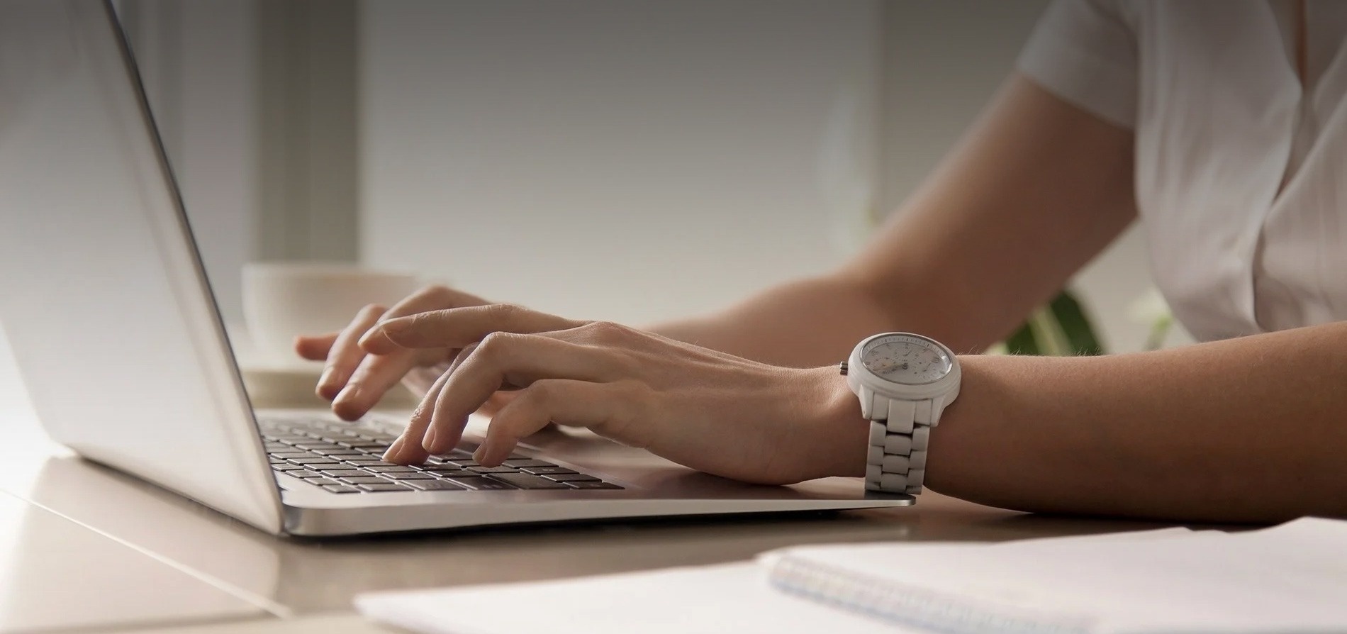 een vrouw met een horloge op haar pols typt op een laptop