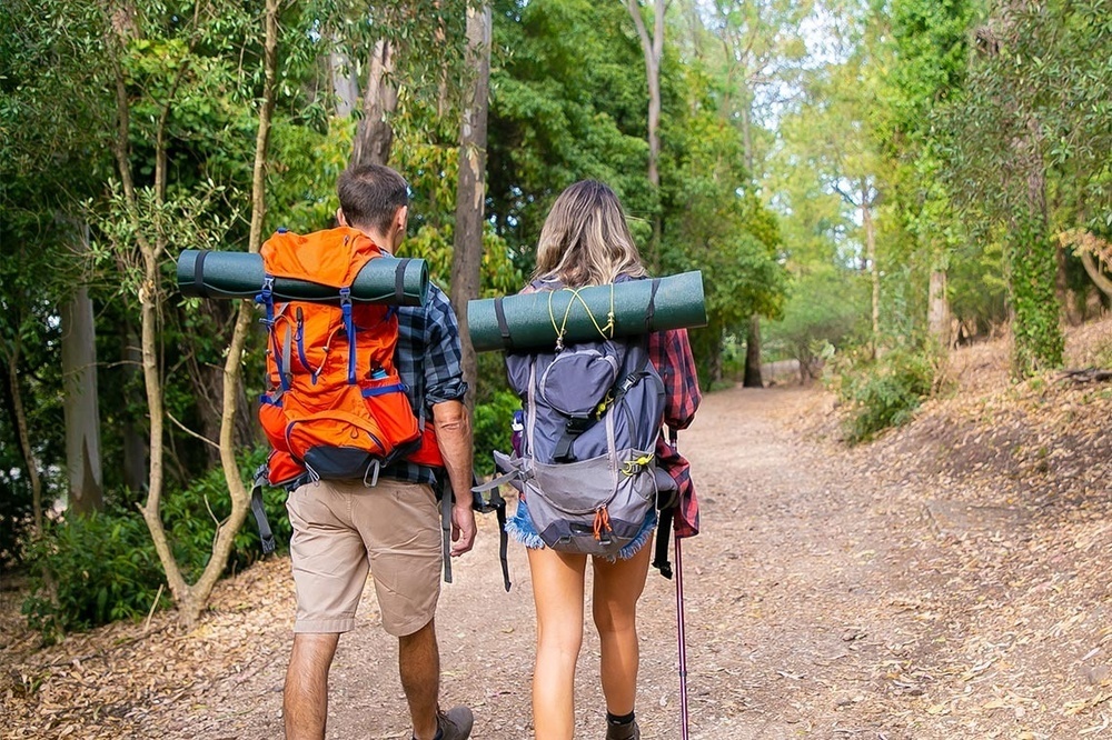 un home i una anciana amb mochilas camina por un sendero