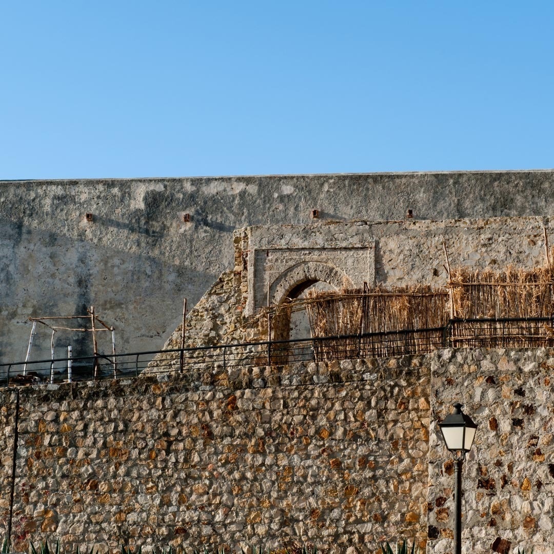 eine Steinmauer mit einem Tor und einem Zaun davor