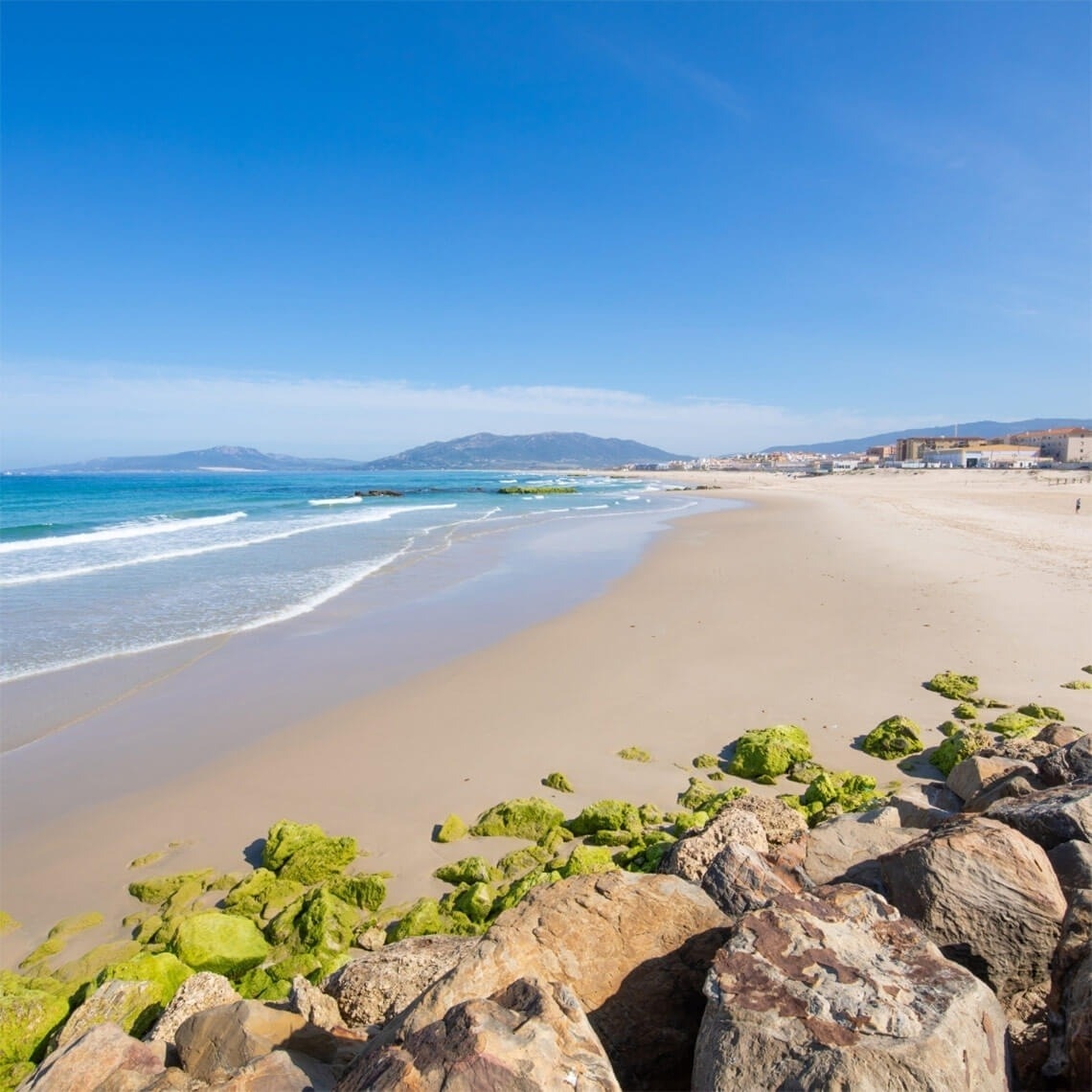 ein Strand mit Blick auf das Meer und eine Stadt im Hintergrund