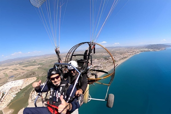 een man geeft een duim omhoog terwijl hij in een parachute vliegt