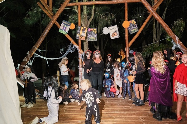 een groep kinderen in halloweenkostuums staan op een houten vloer