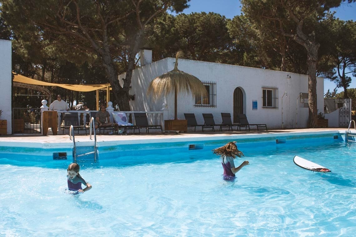 twee meisjes zwemmen in een zwembad met een surfplank