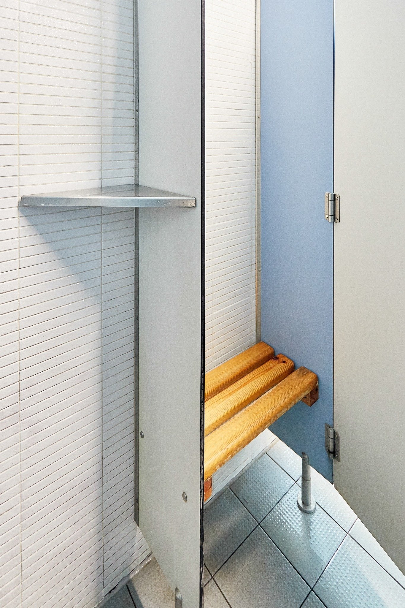 een kleedkamer met een blauwe deur en een houten bank