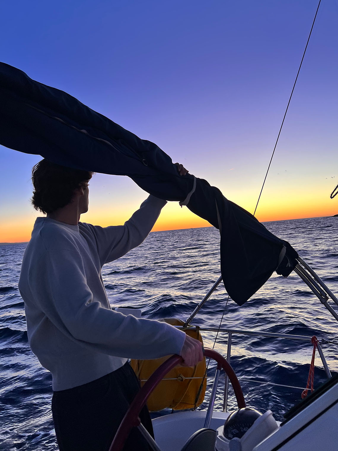 Home a vela al capvespre, amb una persona al timó. Taiga: Corporativa