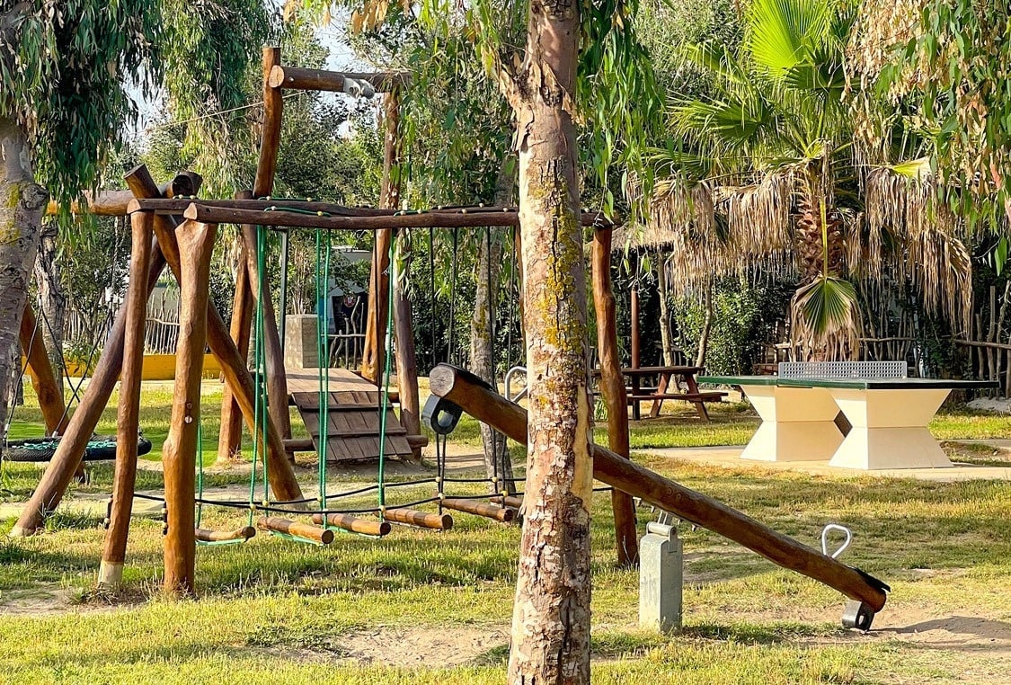 a wooden playground with a ping pong table in the background