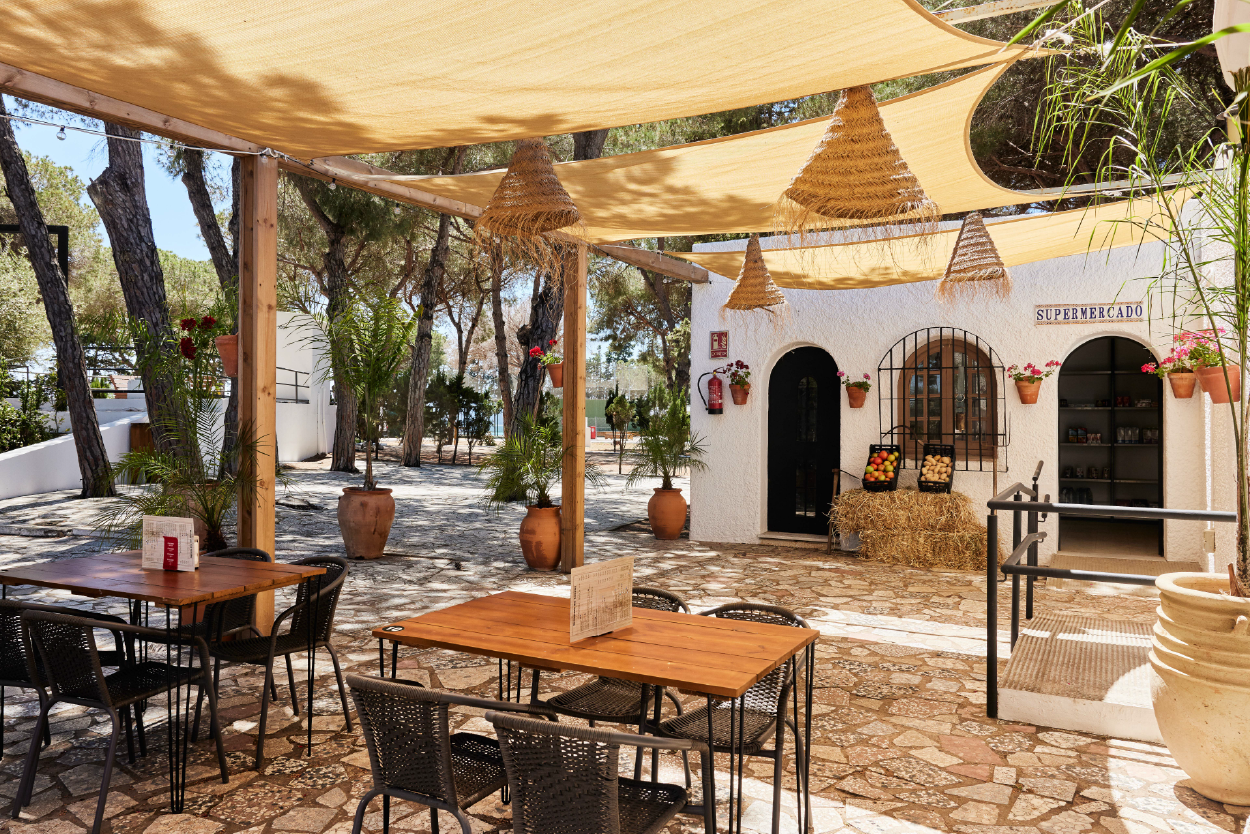 een patio met tafels en stoelen en een bord met de woorden supermercado