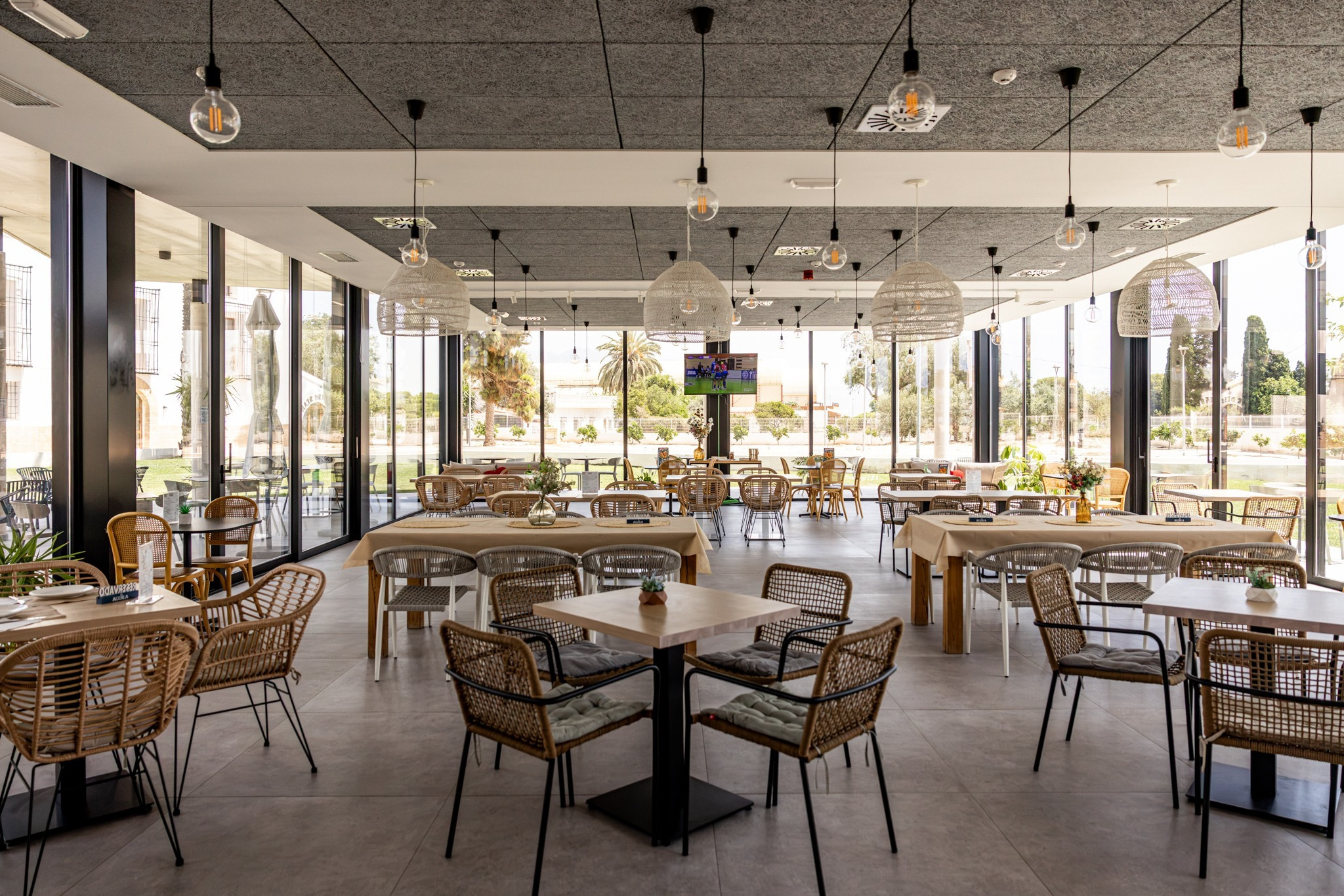 Espacioso comedor de hotel con mesas y sillas de mimbre, luz natural y aire acondicionado. Taiga: Corporativa